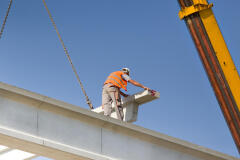 Unsafe construction worker without a harness working at a height on a beam