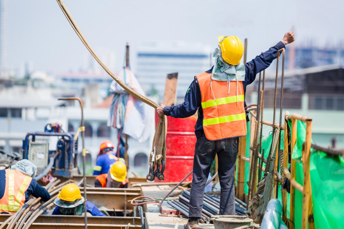 Construction worker communicating with crane operator using nonverbal hand signals in a noisy environment