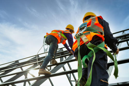 two construction workers wearing fall protection while working